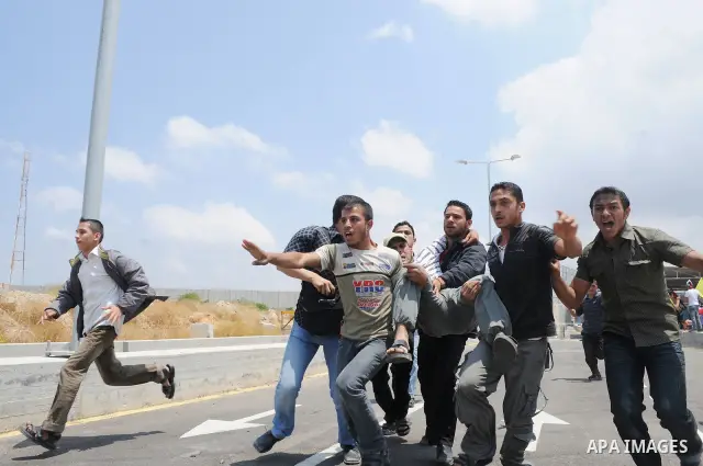 Palestinians carry a wounded protester after Israeli troops opened fire during a massive march heading towards the Erez border crossing in the northern Gaza Strip, on May 15, 2011, as people gathered to mark the "nakbah"...