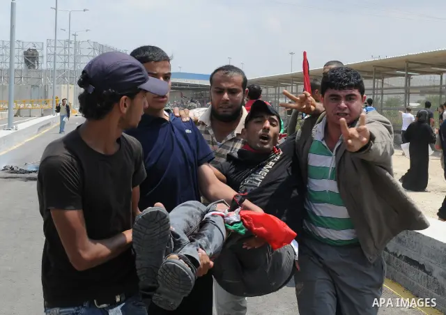 Palestinians carry a wounded protester after Israeli troops opened fire during a massive march heading towards the Erez border crossing in the northern Gaza Strip, on May 15, 2011, as people gathered to mark the "nakbah"...