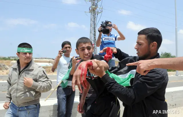 Palestinians carry a wounded protester after Israeli troops opened fire during a massive march heading towards the Erez border crossing in the northern Gaza Strip, on May 15, 2011, as people gathered to mark the "nakbah"...