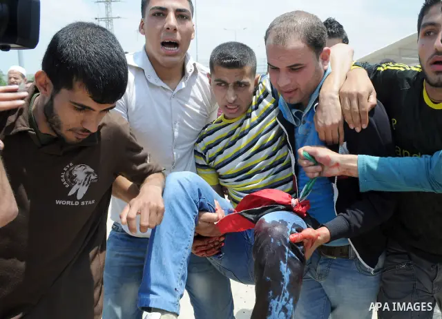 Palestinians carry a wounded protester after Israeli troops opened fire during a massive march heading towards the Erez border crossing in the northern Gaza Strip, on May 15, 2011, as people gathered to mark the "nakbah"...