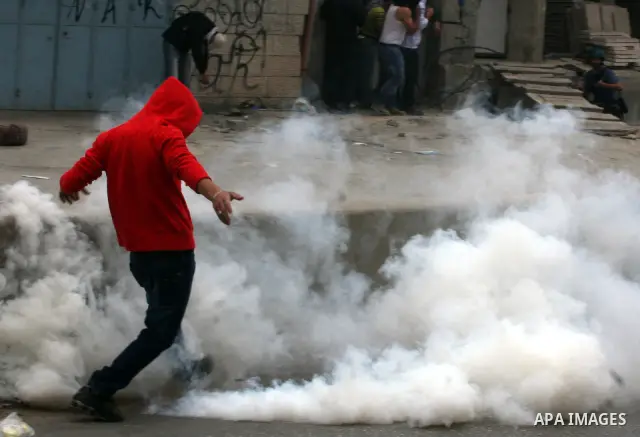 A Palestinian youth throws back a tear gas canister during clashes with Israeli soldiers at the Israeli manned Qalandia checkpoint between Jerusalem and the West Bank city of Ramallah on May 15, 2011. Palestinians across...