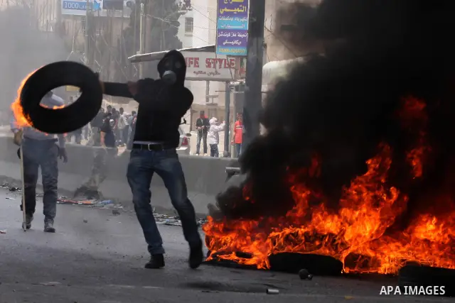 A Palestinian moves a burning tire as Israeli soldiers clashed with Palestinian stone throwers at the Israeli manned Qalandia checkpoin between Jerusalem and the West Bank city of Ramallah on May 15, 2011. Palestinians a...