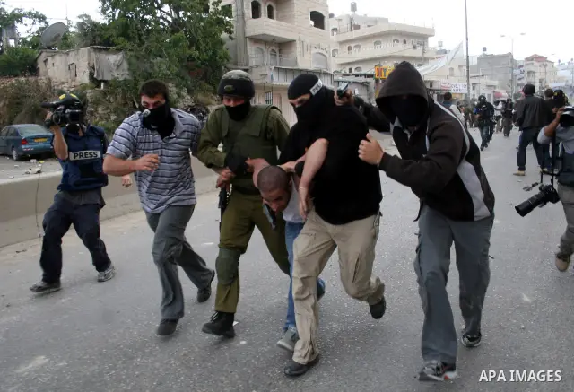 An Israeli soldier and undercover police arrest a Palestinian man during clashes with stone throwers at the Israeli manned Qalandia checkpoint between Jerusalem and the West Bank city of Ramallah on May 15, 2011. Palesti...
