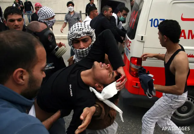 A Palestinian youth is carried away as Israeli soldiers fire tear gas canisters during clashes with Palestinian stone throwers at the Israeli manned Qalandia checkpoint between Jerusalem and the West Bank city of Ramalla...