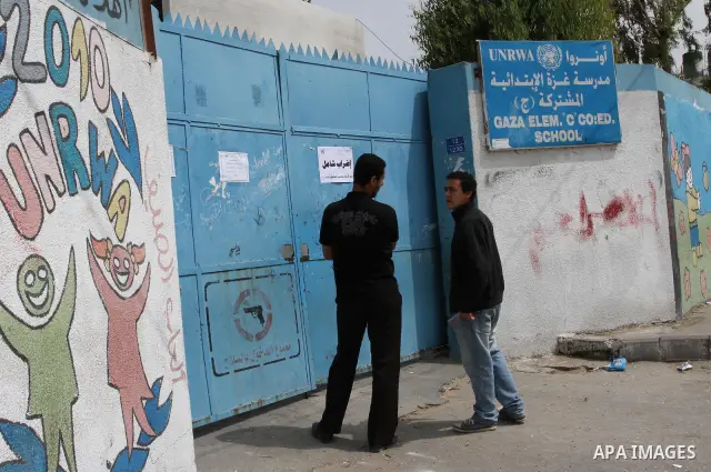 Palestinian men stand in front of United Nations Relief and Works Agency (UNRWA) closed school in Gaza City May 18, 2011 as UN Palestinian employees stage a one day-strike demanding higher wages. Some 16 thousand Palesti...