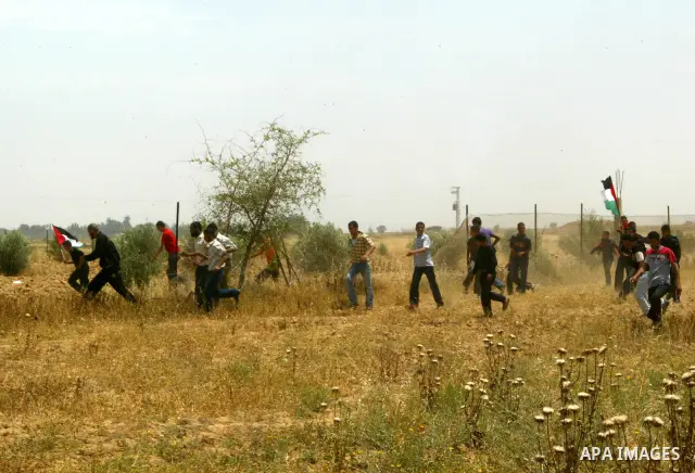 Palestinian youths wave their national flag during a protest near the town of Khan Yunis, close to the border between Israel and the southern Gaza Strip, on May 20, 2011. Photo by Abed Rahim Khatib