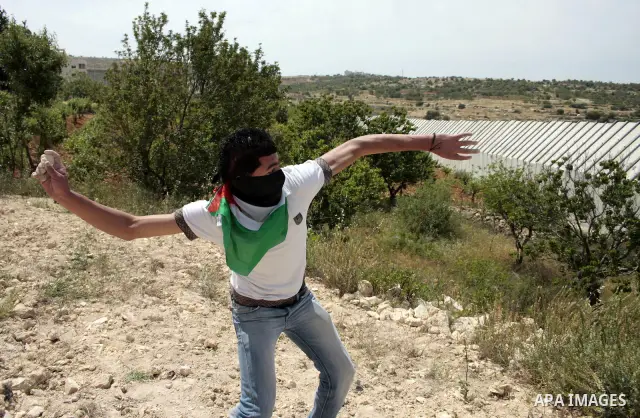 Masked Palestinian demonstrators hurl stones toward Israeli soldiers during a demonstration in the West Bank village of Al-khader near Bethlehem, Friday, May 20, 2011. President Barack Obama on Thursday finally uttered t...
