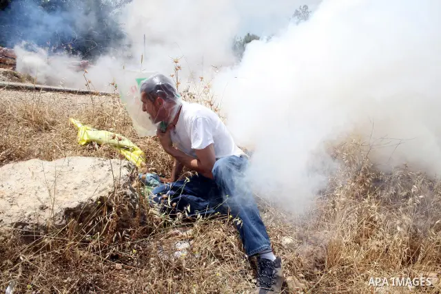 Palestinian demonstrators run for cover from tear gas canisters fired by Israeli soldiers during the weekly demonstration against Israel's separation barrier in the West Bank village of Bilin, near Ramallah, Friday, May...