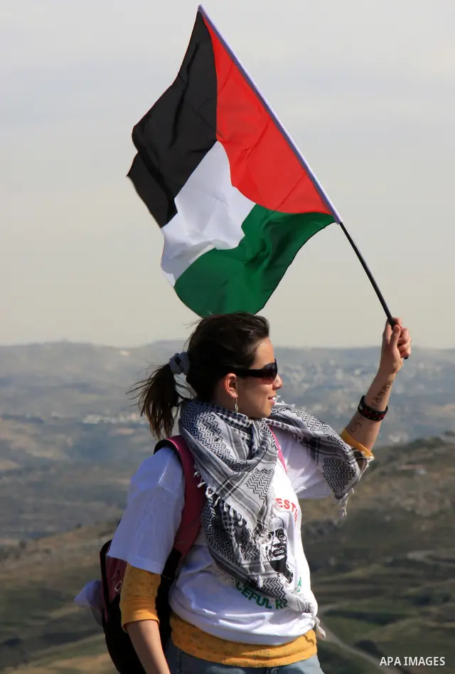 A foreign protester waves with Palestinian flag in front of Israeli soldiers, during a demonstration against Jewish settlements in the northern West Bank village of Iraq Burin, near Nablus, Saturday, May 21, 2011. Photo...