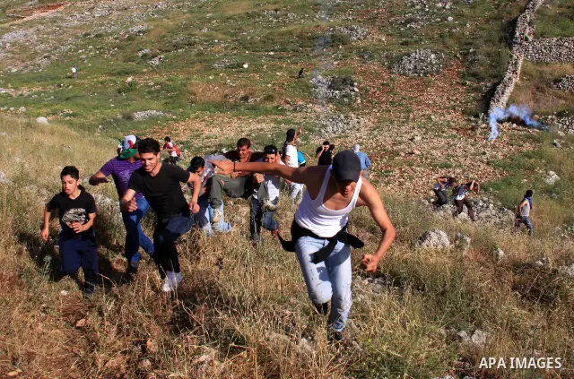 Palestinian and foreign protesters run from tear gas fired by Israeli soldiers, during a demonstration against Jewish settlements in the northern West Bank village of Iraq Burin, near Nablus, Saturday, May 21, 2011. Phot...