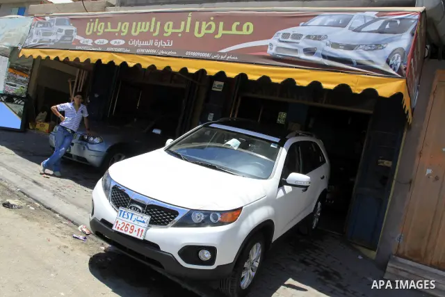 Palestinians watch a new car that Israel recently allowed into Gaza, at a showroom in Gaza City, on May 23, 2011. Luxury cars with Libyan plates are becoming a common sight in the Gaza Strip, in a surprising side-effect...