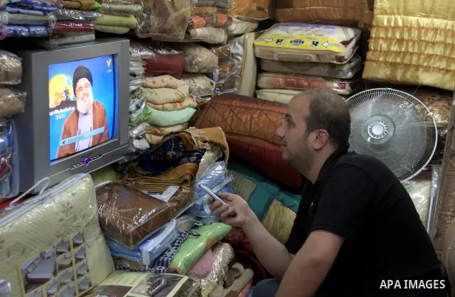 A Palestinian vendor watches TV during a speech by Hassan Nasrallah at his shop in the West Bank city of Nablus on May 25, 2011. Photo by Wagdi Eshtayah