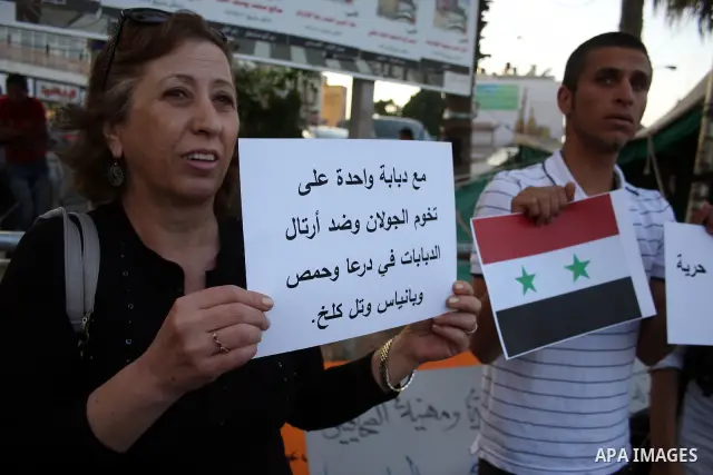 Palestinians hold Syrian flags and signs as they join a demonstration in the West Bank city of Ramallah on May 26, 2011 in support of the Syrian opposition as Syria's pro-democracy movement has reached out to the army ah...