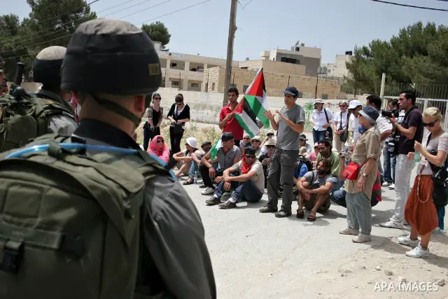 Israeli soldiers stand guard near Palestinians and foreign peace activists taking part in a demonstration against Israel's controversial separation barrier in the West Bank village of Maasarah, near Bethlehem, on May 27,...