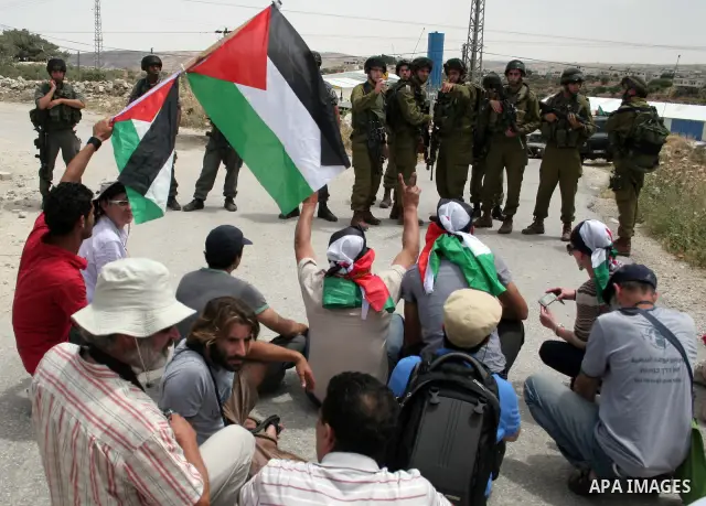 Israeli soldiers stand guard near Palestinians and foreign peace activists taking part in a demonstration against Israel's controversial separation barrier in the West Bank village of Maasarah, near Bethlehem, on May 27,...