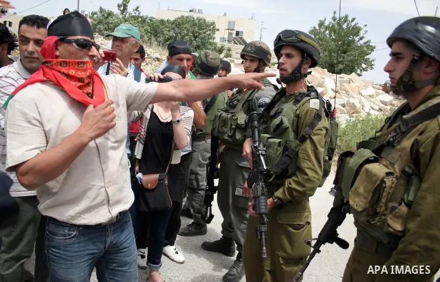 Israeli soldiers stand guard near Palestinians and foreign peace activists taking part in a demonstration against Israel's controversial separation barrier in the West Bank village of Maasarah, near Bethlehem, on May 27,...