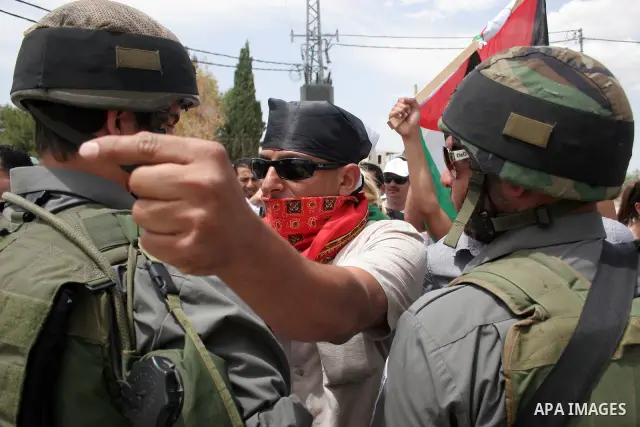 Israeli soldiers stand guard near Palestinians and foreign peace activists taking part in a demonstration against Israel's controversial separation barrier in the West Bank village of Maasarah, near Bethlehem, on May 27,...