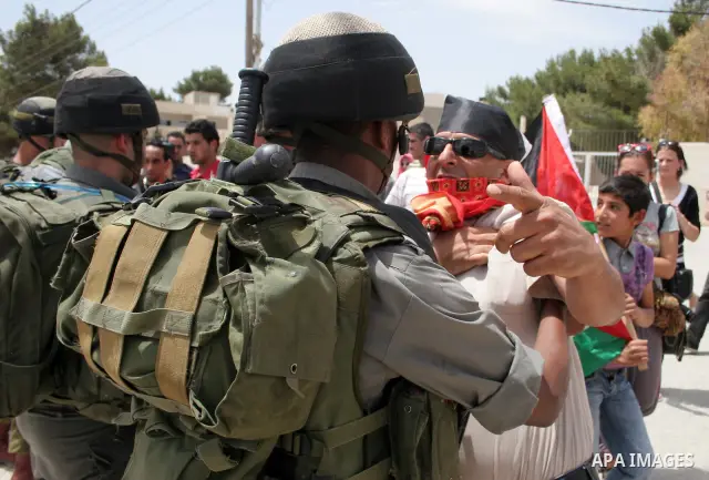Israeli soldiers stand guard near Palestinians and foreign peace activists taking part in a demonstration against Israel's controversial separation barrier in the West Bank village of Maasarah, near Bethlehem, on May 27,...