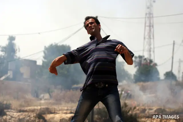 A Palestinian protester hurls stones toward Israeli soldiers during a protest against the expropriation of Palestinian land to expand the Jewish settlement of Halmish, in the West Bank village of Nabi Saleh, on May 27, 2...