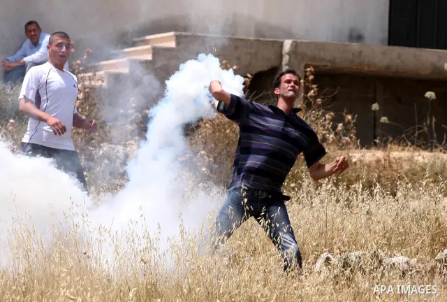 A Palestinian protester hurls back a tear gas canister toward Israeli soldiers during a protest against the expropriation of Palestinian land to expand the Jewish settlement of Halmish, in the West Bank village of Nabi S...