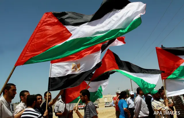 Palestinians wave with their national flag and Egyptian flag at Rafah border crossing in the southern Gaza Strip on May 28, 2011 as Egypt reopened the border, allowing people to cross freely for the first time in four ye...