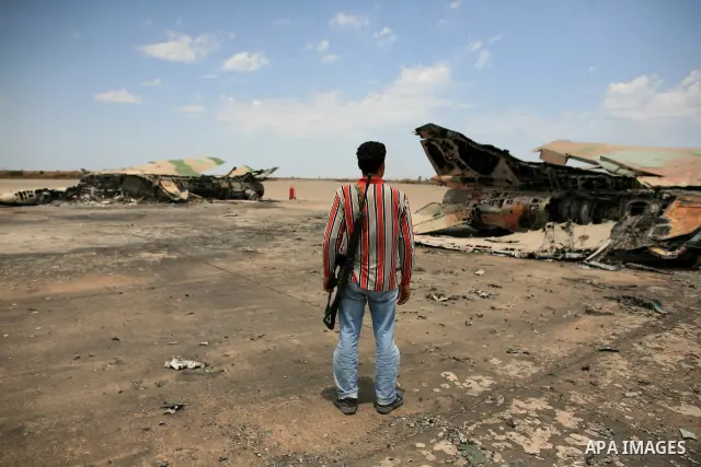 Libyan rebel fighters stand near a destroyed fighter plane belonging to forces loyal to Muammar Gaddafi at the airport of Misrata, Libya, May 28, 2011. Photo by Wissam Nassar