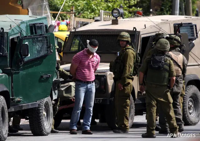 Israeli army forces arrest a man during a raid in the West Bank city of Ramallah on May 30, 2011. Five Palestinians were arrest, three from the village of Amrine, near the northern West Bank city of Nablus and two others...
