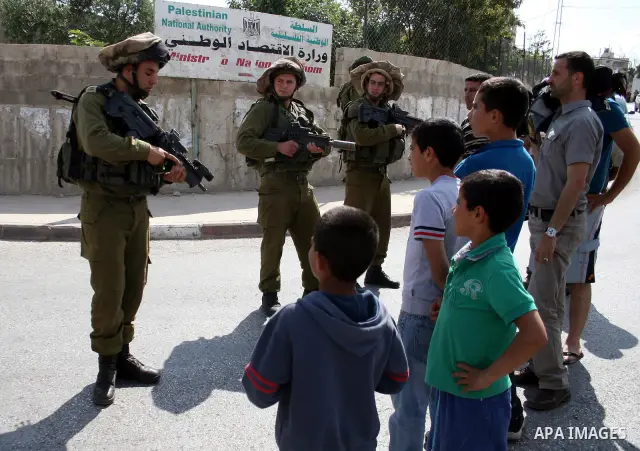 Israeli border guards stand guard near Palestinian civilians during a raid in the West Bank city of Ramallah on May 30, 2011. Five Palestinians were arrest, three from the village of Amrine, near the northern West Bank c...