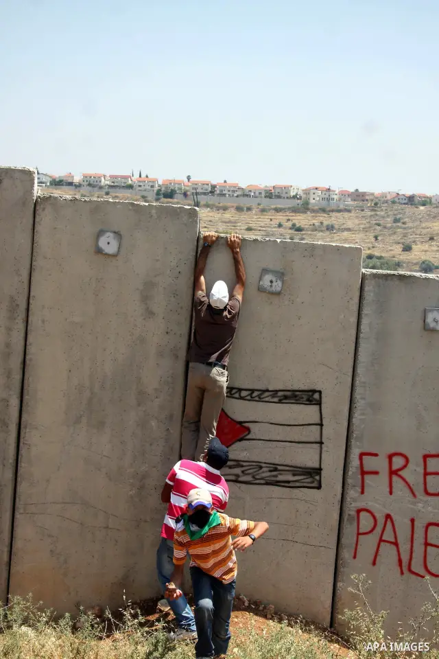 A Palestinian demonstrator tries to climb the Israel's separation barrier during a protest in the West Bank village of Nilin, near Ramallah, Friday, June 3, 2011. Photo by Issam Rimawi