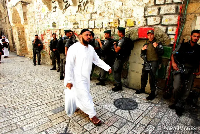 A Palestinian Muslim worshiper walk past Israeli soldiers after Friday prayer in Jerusalem's Old City on June 03, 2011 as Israeli police restricted the entrance age to men over 45 at the Al Aqsa Mosque compound in fear o...