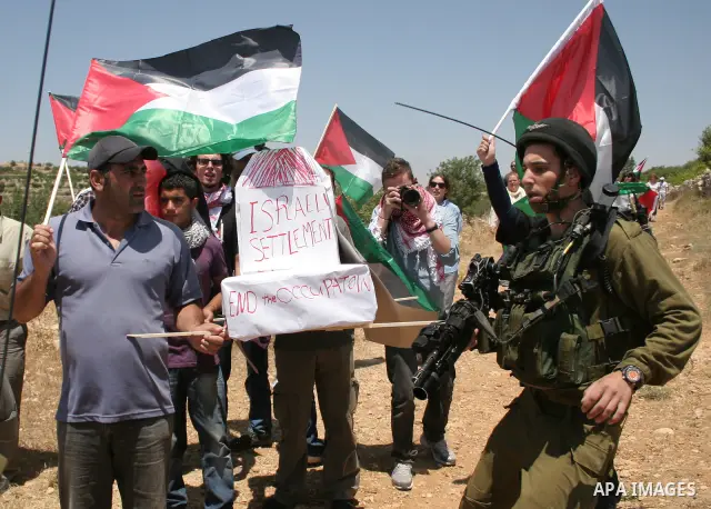 Israeli soldiers stand guard as Palestinians hold up a model of Jewish settlement during a demonstration by foreign, Israeli and Palestinian activists against the Jewish settlement of Karmei Tzur near the Palestinian vil...