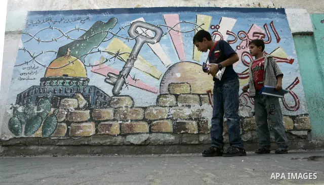 Palestinian boys stand in front of a mural painting on the theme of return of refugees in Rafah in southern Gaza Strip on June 5, 2011. Today sunday marking the 44th anniversary of 'Naksa,' Arabic for setback, of the ann...