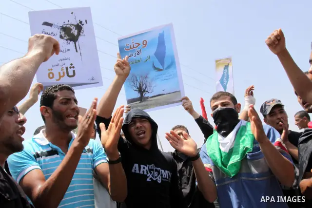 Palestinian protesters wave Palestinian national flags during a demonstration and Members of Hamas' security forces holds back protesters from reaching Erez border crossing in the northern Gaza Strip, on June 5, 2011, to...