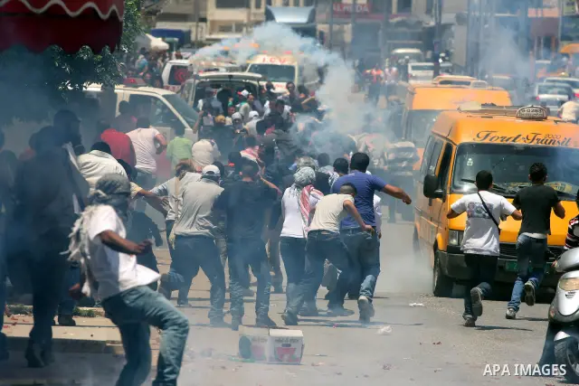 Palestinian demonstrators run for cover from tear gas canisters fired by Israeli soldiers during a protest marking the 44th anniversary of the Six Days War on June 5, 2011 at the Israeli-controlled Qalandia checkpoint be...
