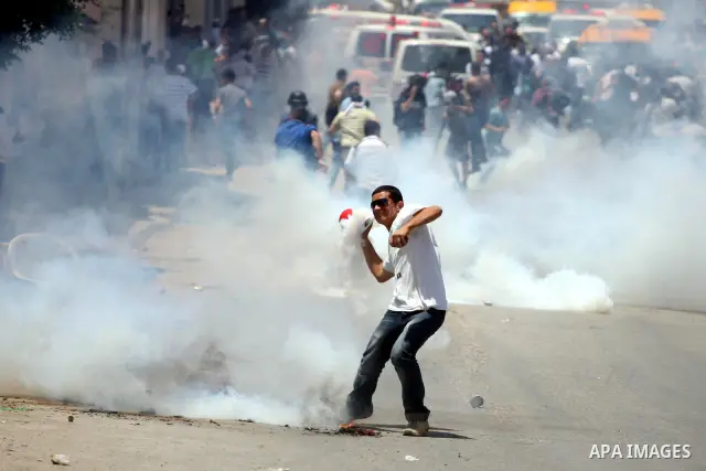 Palestinian demonstrators run for cover from tear gas canisters fired by Israeli soldiers during a protest marking the 44th anniversary of the Six Days War on June 5, 2011 at the Israeli-controlled Qalandia checkpoint be...