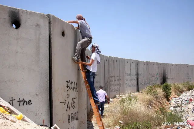 Palestinians climb over the controversial Israeli built separation barrier as clashes break out between Israeli security and Palestinian activists during a protest marking the 44th anniversary of the Six Days War on June...