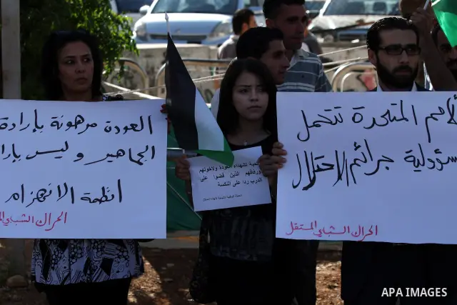 Palestinians shout slogans and hold their national flag as they demonstrate in the West Bank city of Ramallah on June 6, 2011 in respect to those who were killed a day earlier by Israeli soldiers during a protest marking...
