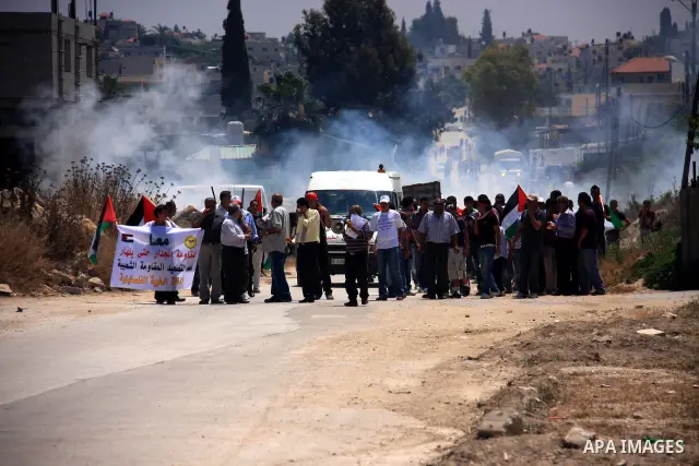 Palestinians youth, Israelis and foreign demonstrators run from tear gas fired by Israeli troops during clashes following a protest against Israel's separation barrier in the village Nazlet Issa north Tulkarm in the West...