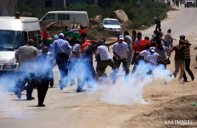 Palestinians youth, Israelis and foreign demonstrators run from tear gas fired by Israeli troops during clashes following a protest against Israel's separation barrier in the village Nazlet Issa north Tulkarm in the West...