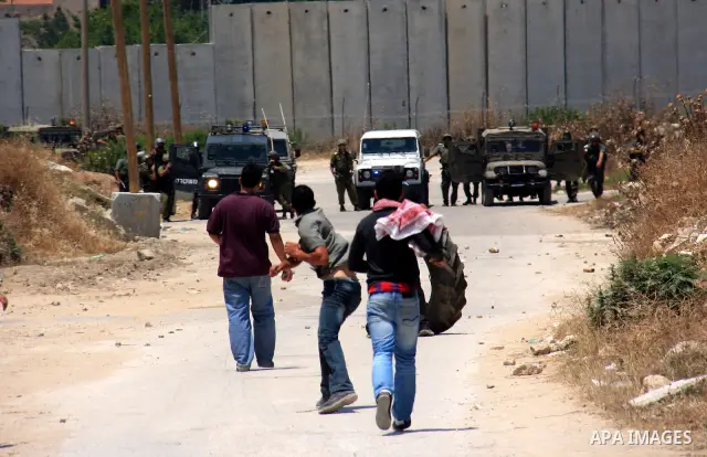 Palestinian youths throw stones at Israeli soldiers following a protest against Israel's separation barrier in the village Nazlet Issa north Tulkarm in the West Bank on June 7, 2011. Photo by Wagdi Eshtayah
