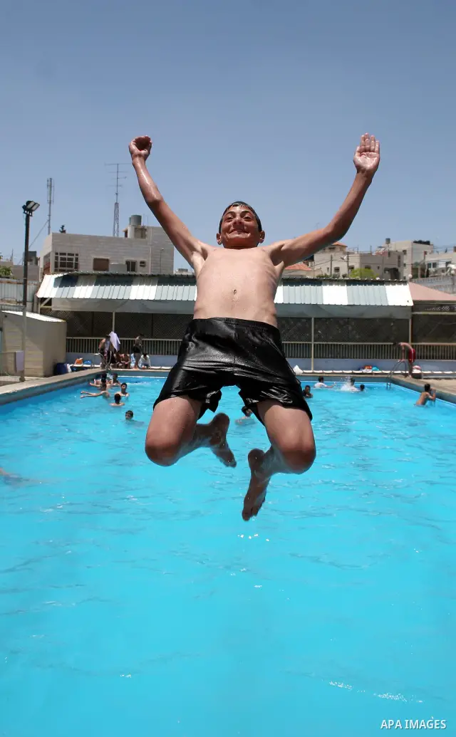 A Palestinian boy enjoys swimming in the swimming pool to feel relaxation after completion of their school examinations and the end of schools year, in the West Bank city of Hebron on June 08,2011. Photo by Najeh Hashlam...
