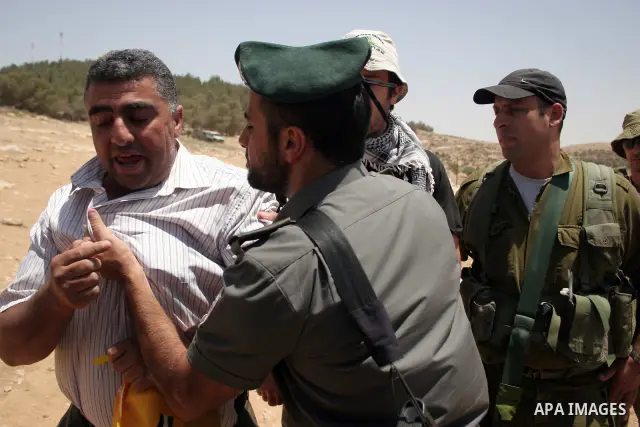 Israeli forces detain a protester during a demonstration by Palestinian and foreign peace activists against Israeli settlements in the West Bank village of Al-Tuwani, near Hebron, on June 10,2011. Photo by Najeh Hashlamo...