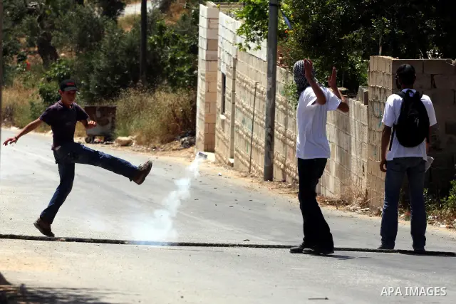 A demonstrator kicks back a tear gas canister fired by Israeli forces during clashes following a protest against the expropriation of Palestinian land, in the village of Nabi Saleh, in the Israeli-occupied West Bank, on...