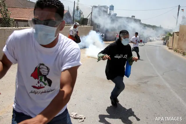 Demonstrators run for cover from tear gas canisters fired by Israeli forces during clashes following a protest against the expropriation of Palestinian land, in the village of Nabi Saleh, in the Israeli-occupied West Ban...
