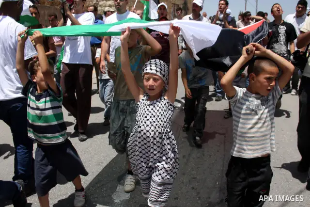 Demonstrators hold a Palestinian flag during a protest against the expropriation of Palestinian land, in the village of Nabi Saleh, in the Israeli-occupied West Bank, on June 10, 2011. Photo by Issam Rimawi