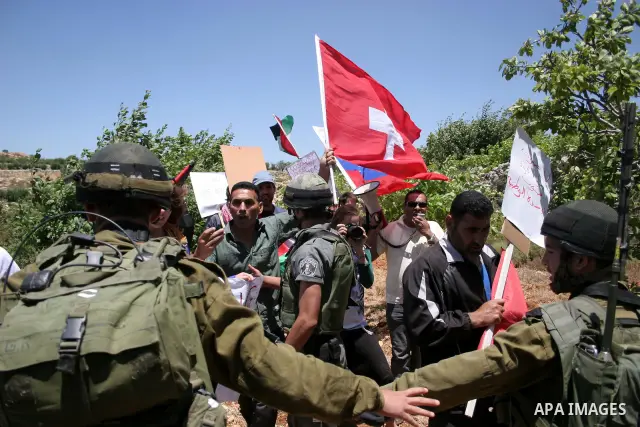 Israeli soldiers stand guard during a demonstration by Palestinian, Israeli and foreign activists against the destroy of farm lands used in the construction of Jewish settlements near the existing Israeli settlement of K...