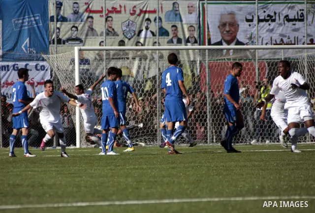 Palestinian players celebrate after a goal during a friendly football match between the Palestinian and Italian Olympic teams to mark the inauguration of the Dura Stadium near the West Bank city of Hebron on June 12, 201...