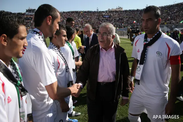 Palestinian prime minister Salam Fayyad shakes hand with Palestinian players during a friendly football match between the Palestinian and Italian Olympic teams to mark the inauguration of the Dura Stadium near the West B...