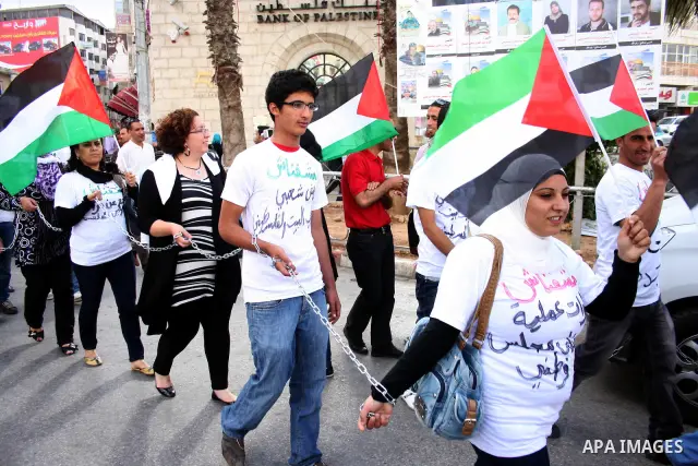 Palestinians hold national flags and banners calling for the release of prisoners for political reasons by the Palestinian security forces during a protest in the West Bank city of Ramallah, on June 13,2011. Photo by Iss...