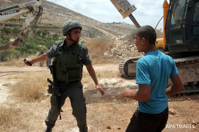 Palestinians argue with Israeli border guards as Israeli army machinery destroy a water reservoir used by Palestinian farmers in Hebron, in the Israeli-occupied West Bank, on June 14,2011. Photo by Najeh Hahlamoun.